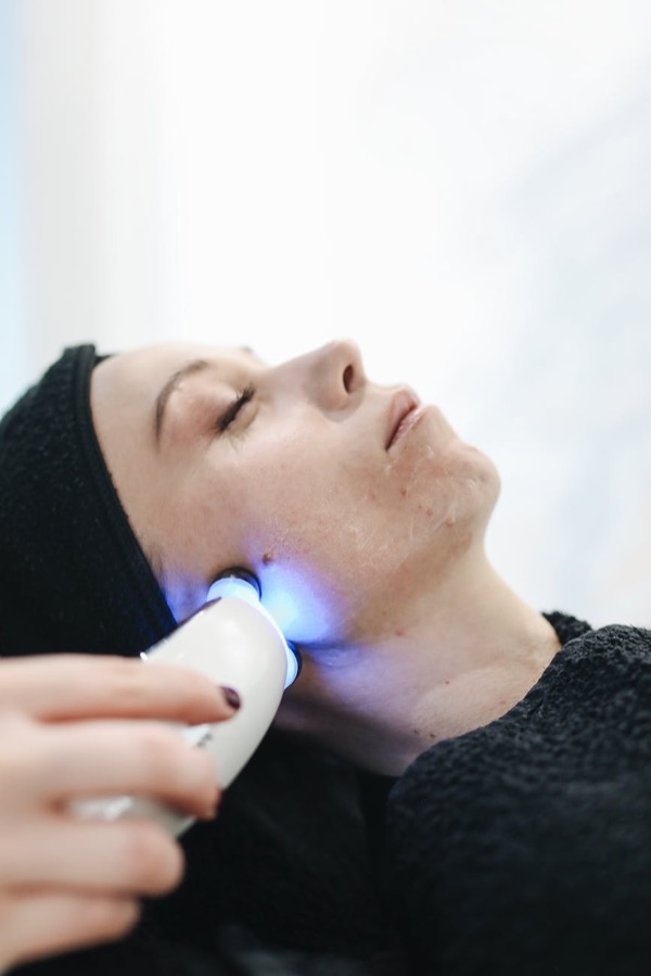Woman receiving LED facial skincare device treatment for radiance boost