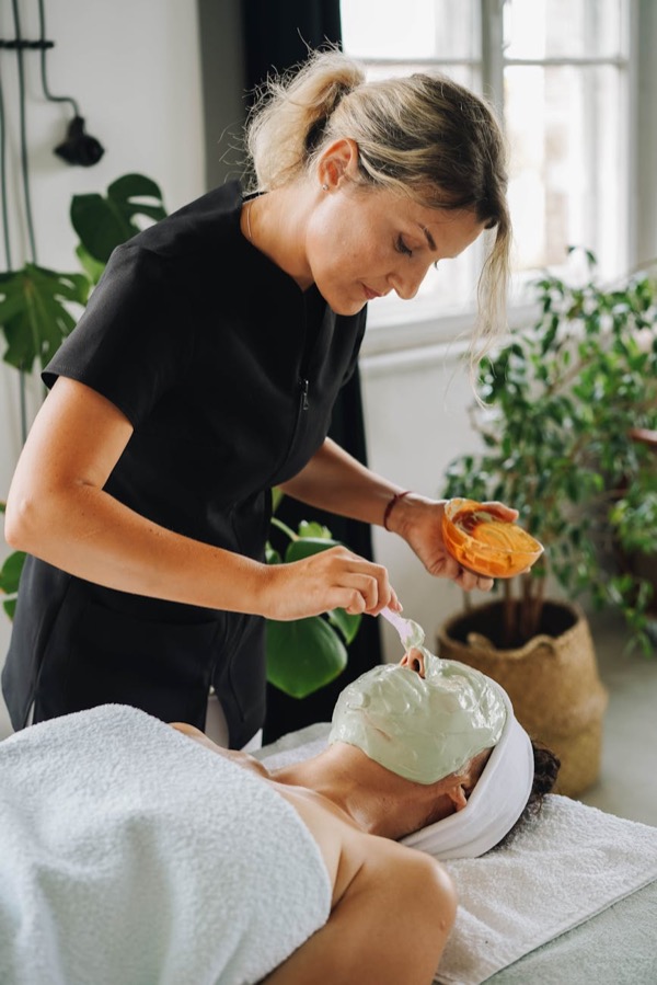 Aesthetician applying facial mask treatment for even skin tone